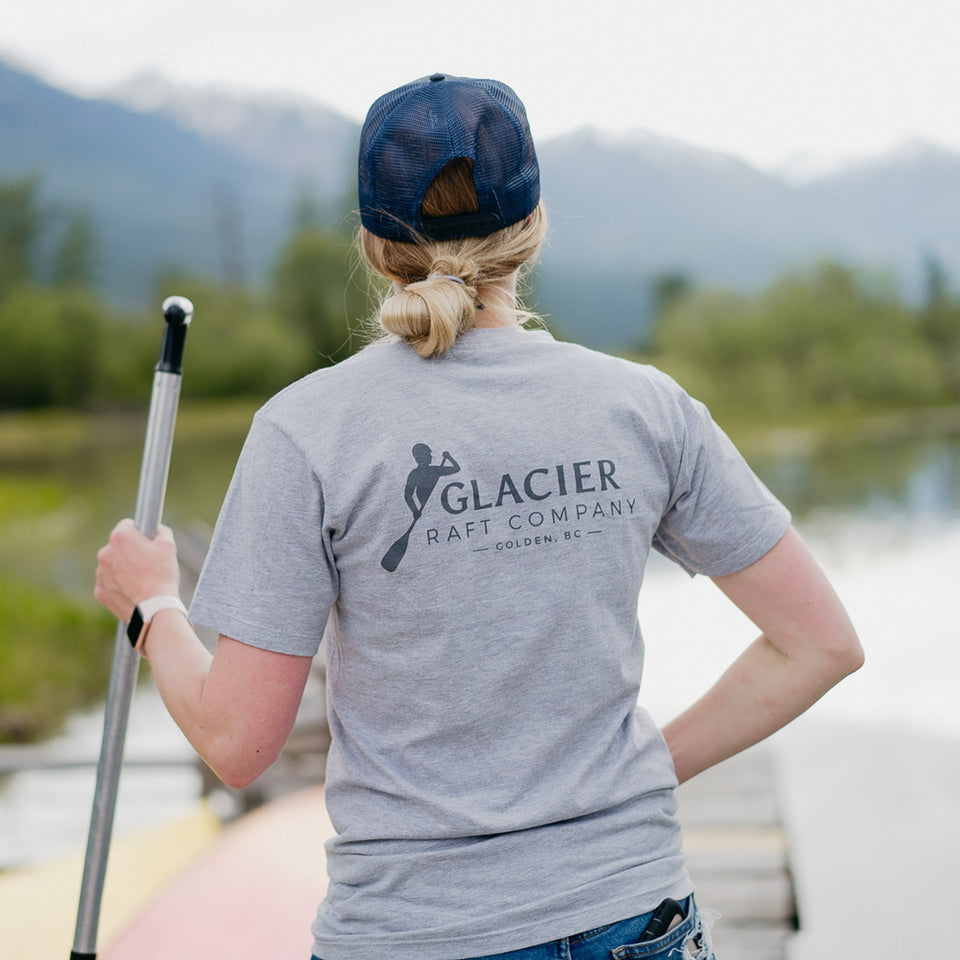 Model wearing a Glacier Raft Company Golden BC logo t-shirt in grey by the Kicking Horse River